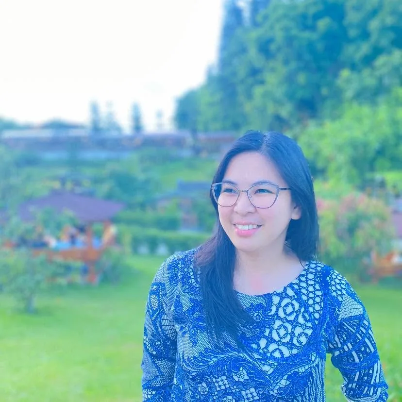 Gillian in a garden wearing a blue patterned top